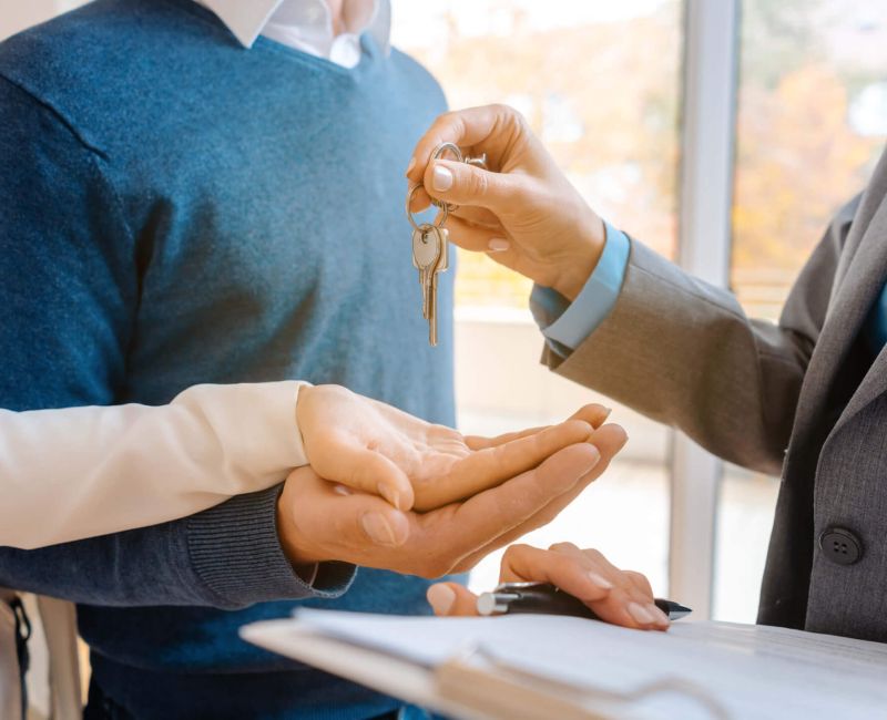 3 Hände Mann gibt Pärchen Schlüssel in die Hand